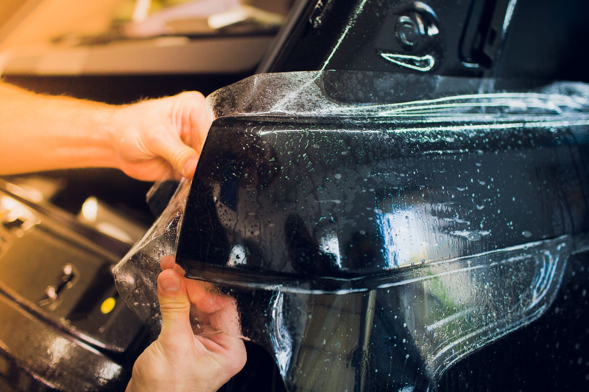 Worker hands installs car paint protection film wrap. Worker hands installs car paint protection film wrap.